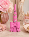Pink coquette bow ring holder with rings displayed on vanity